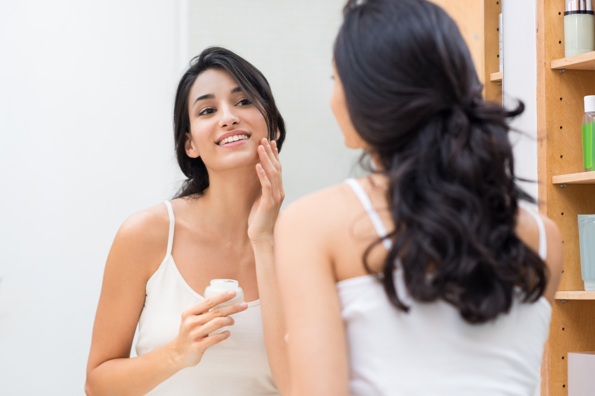 A woman gazes at her reflection in the mirror